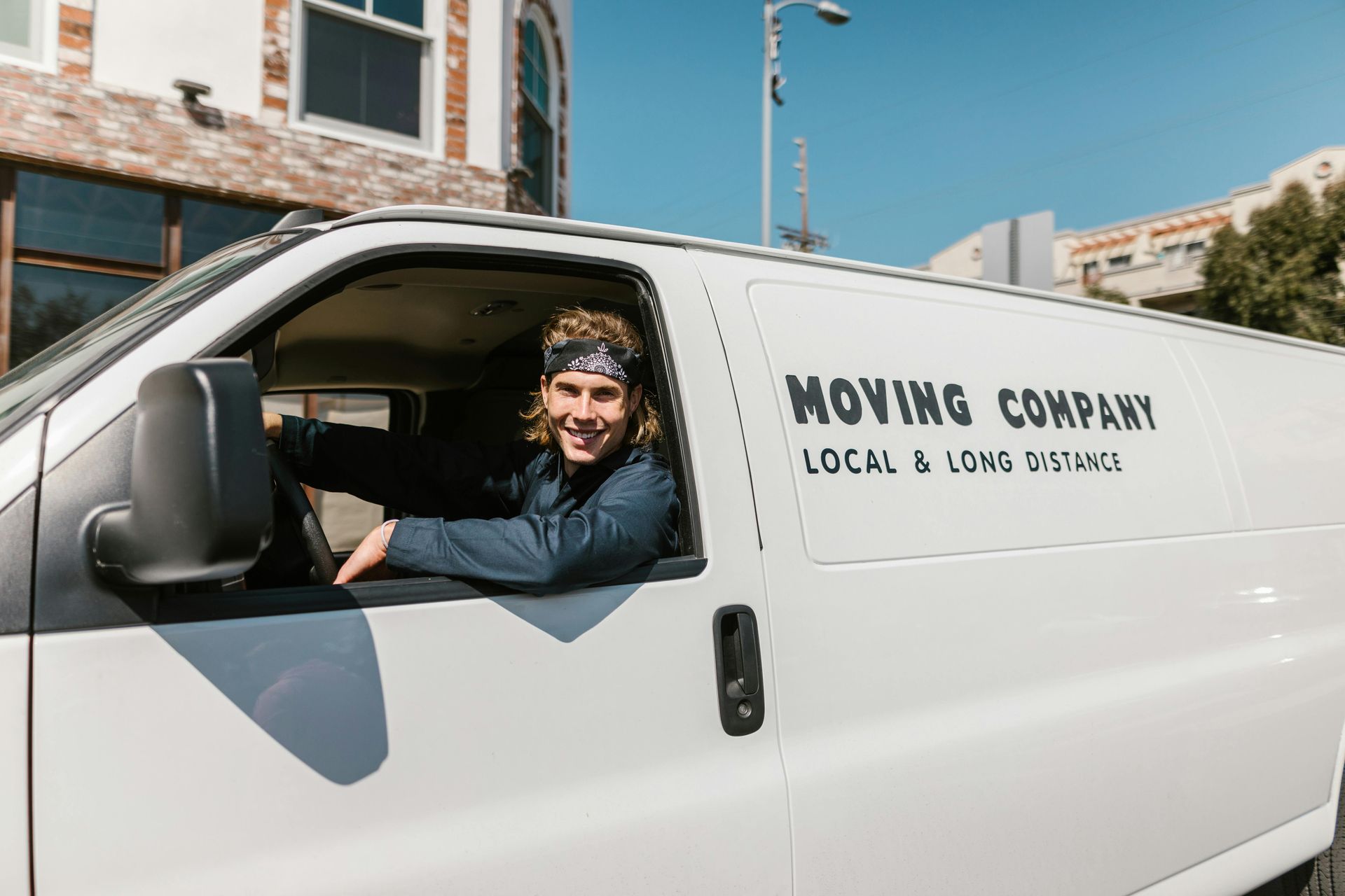Man smiling, driving a white moving van with 