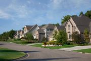 Suburban street with houses; sunny day, green lawns, blue sky.