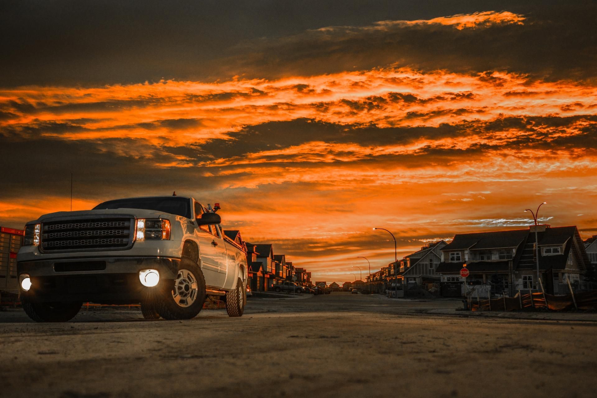 Off-road truck driving on a dirt road at sunset under a dramatic orange sky