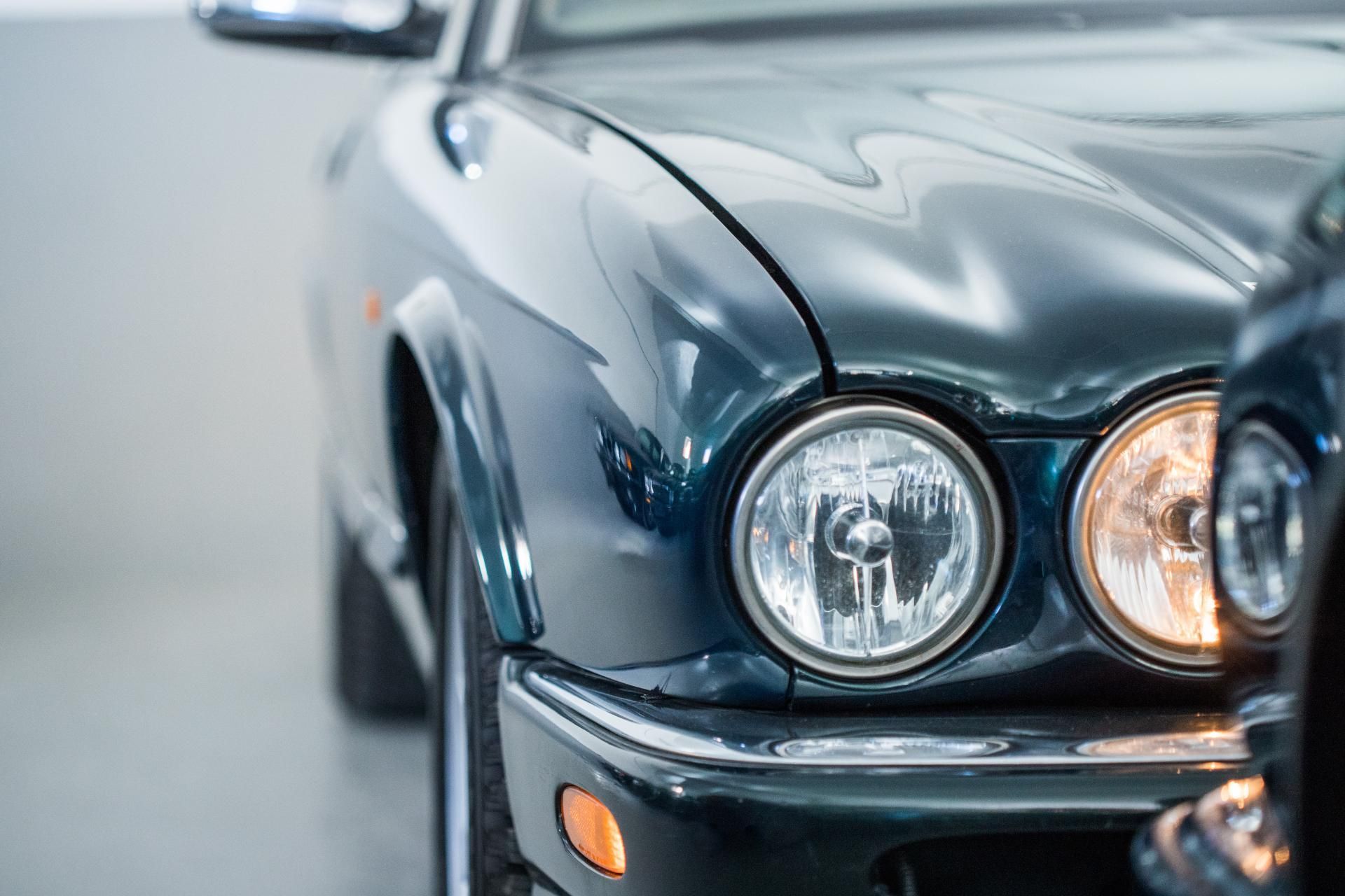 Close-up of a dark blue classic car front with round headlights and chrome details