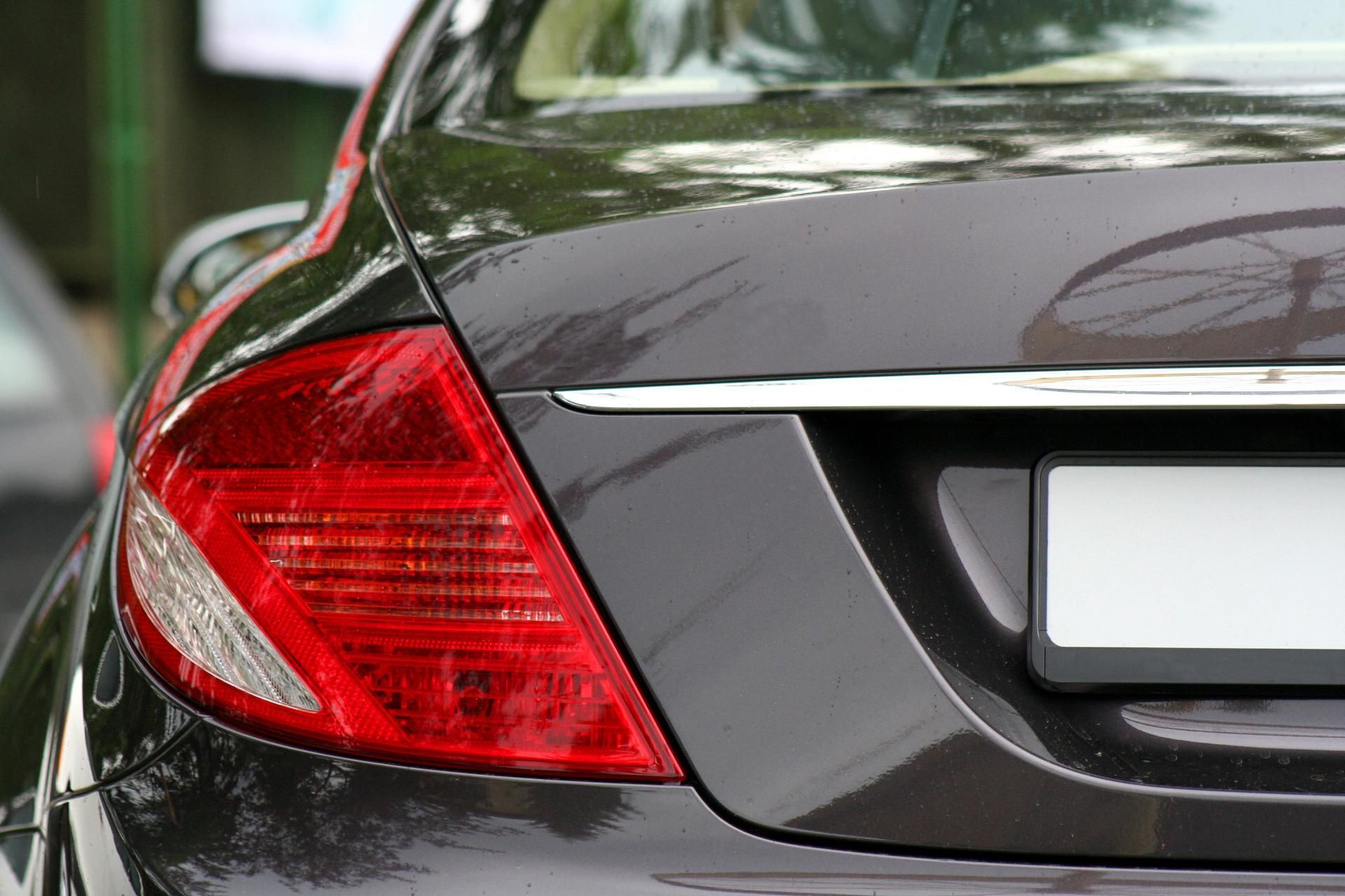 Rear left taillight and trunk of a black car, close-up view