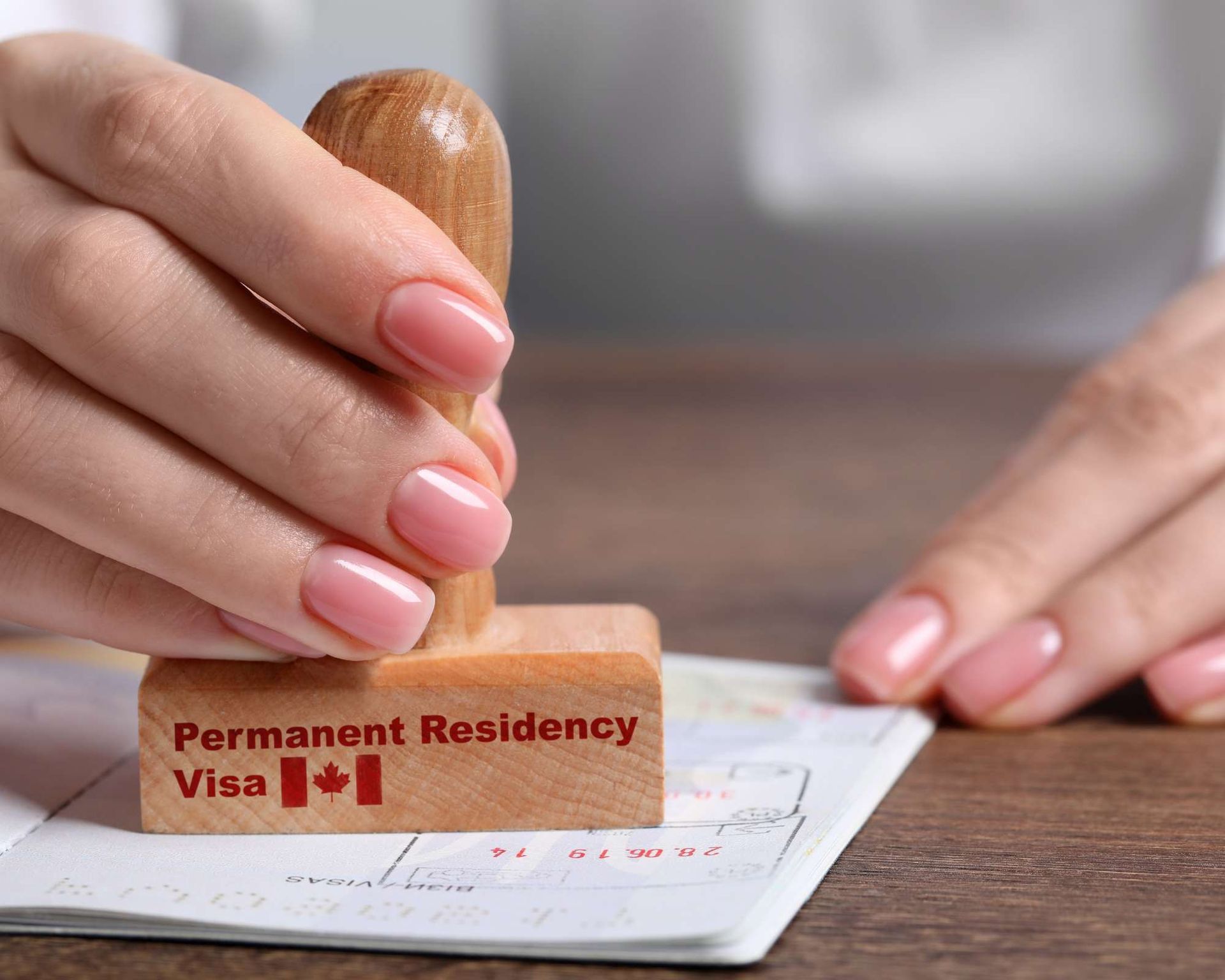 Hand stamping a Canadian Permanent Residency Visa in a passport.