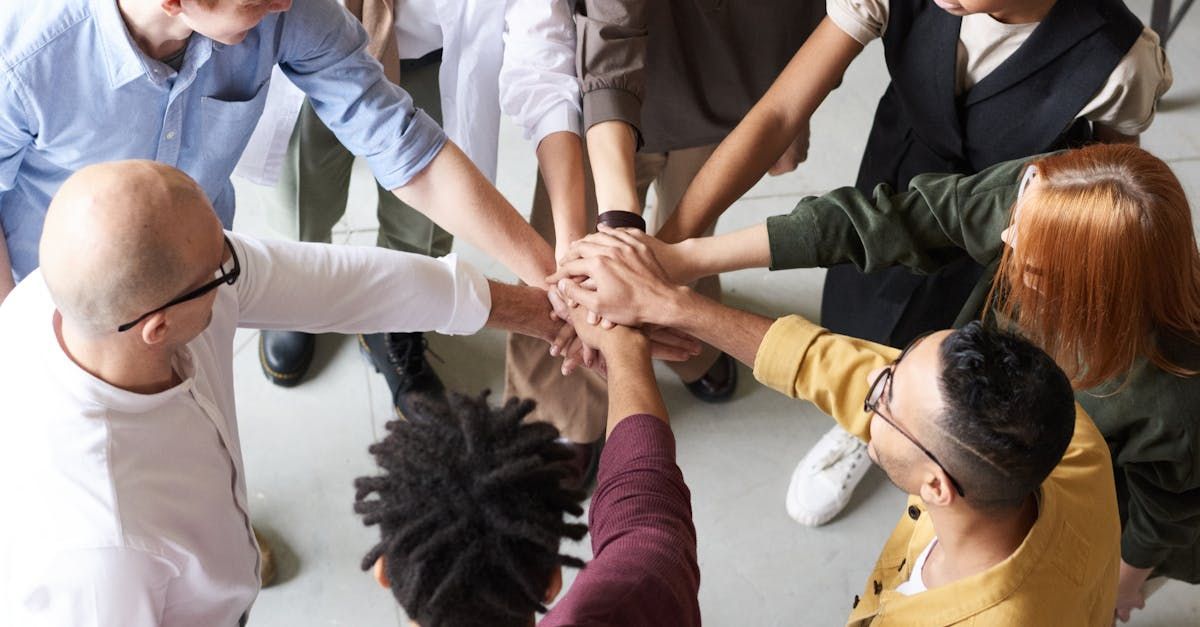 Hands of a diverse group stacked in a team huddle, symbolizing unity and collaboration.