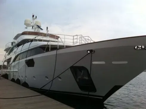 Grande yacht di lusso bianco ormeggiato in acque calme, visto dalla parte anteriore destra.