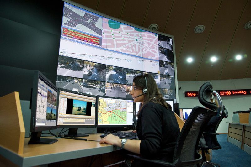 A woman wearing a headset is sitting in front of a computer monitor.