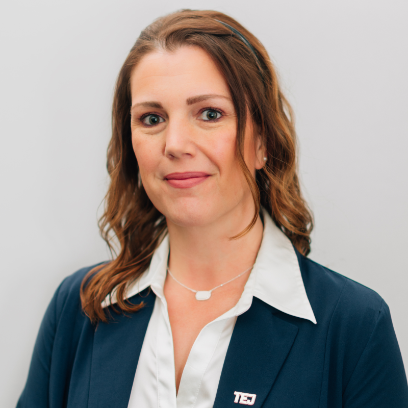 Portrait of a person in a white shirt and navy blazer against a light gray background