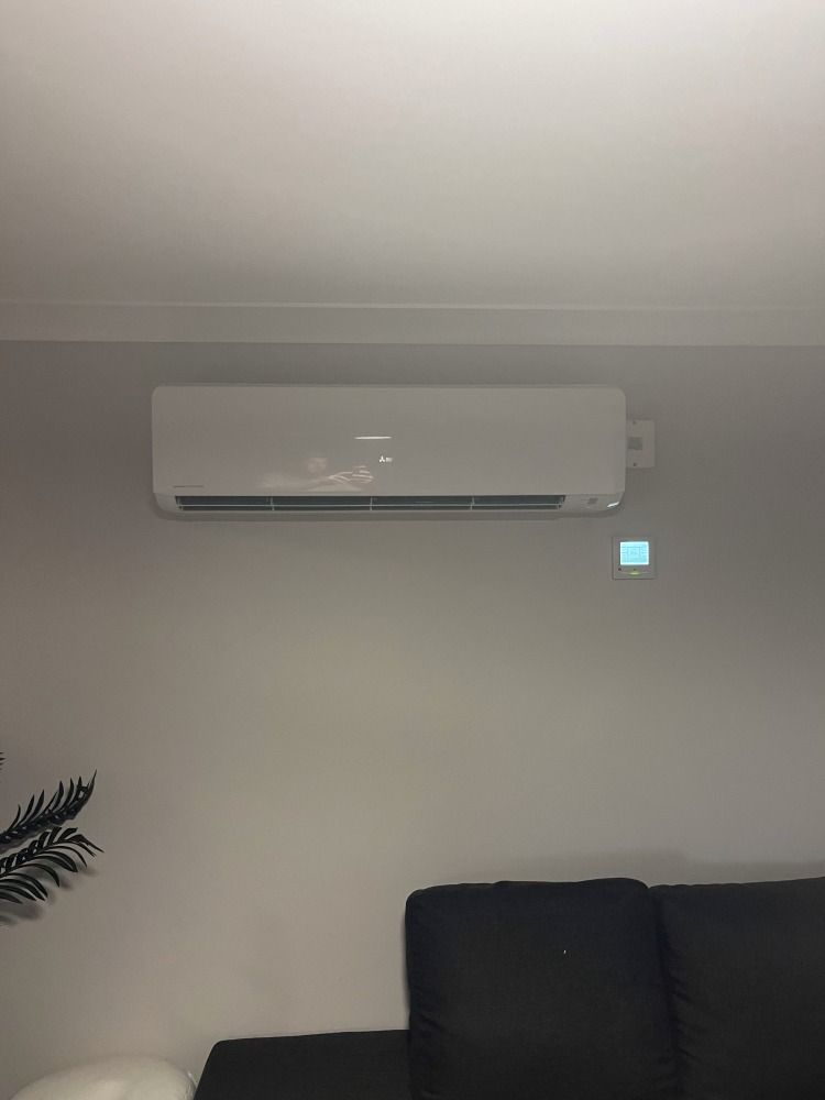 A Living Room With a Couch and a Wall Mounted Air Conditioner — JW Electrical, Air & Solar Pty Ltd in Kew, NSW