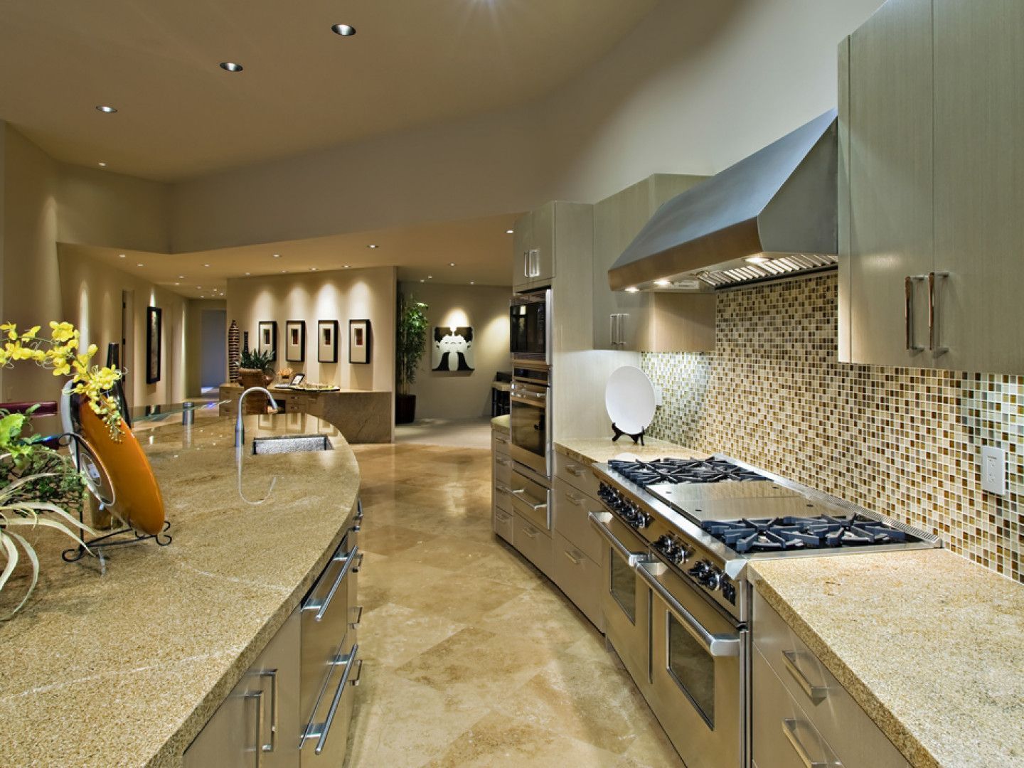 Curved modern kitchen with beige countertops, stainless steel appliances, and mosaic tile backsplash.