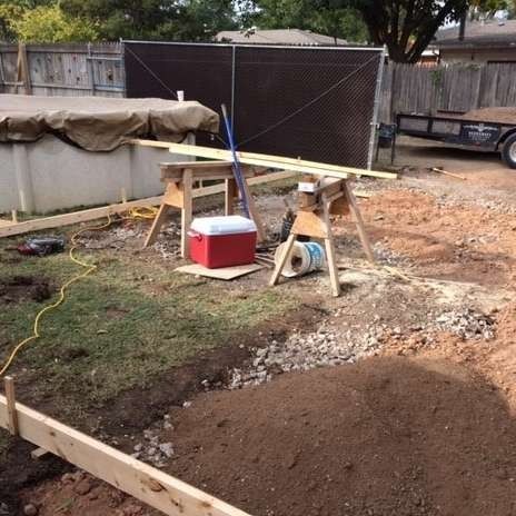 Backyard construction with wood, soil, pool, and tools.