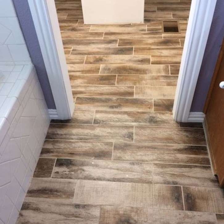 Wood-look tile flooring in a bathroom, with white trim and a partially visible tub.