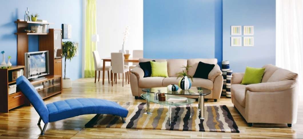 Living room with blue and beige furniture, wooden floors, and blue walls.