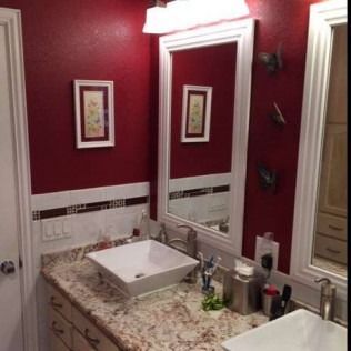 Bathroom with red walls, white trim, and a vanity with a sink and mirror.