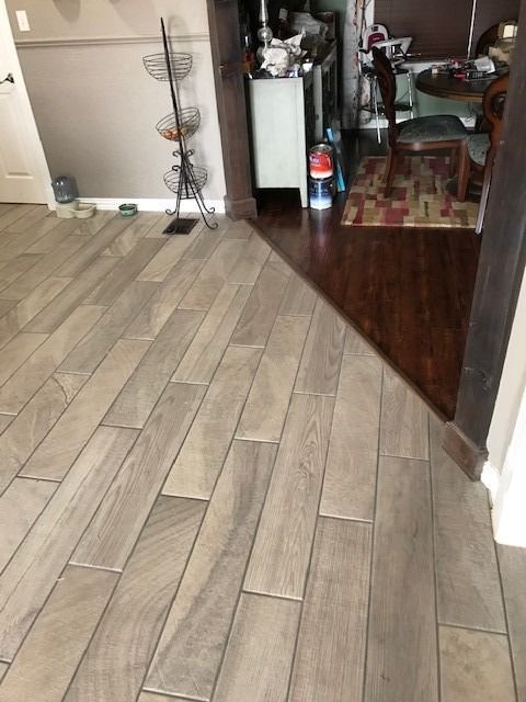 Light wood-look tile flooring transitions to dark wood flooring in a doorway.