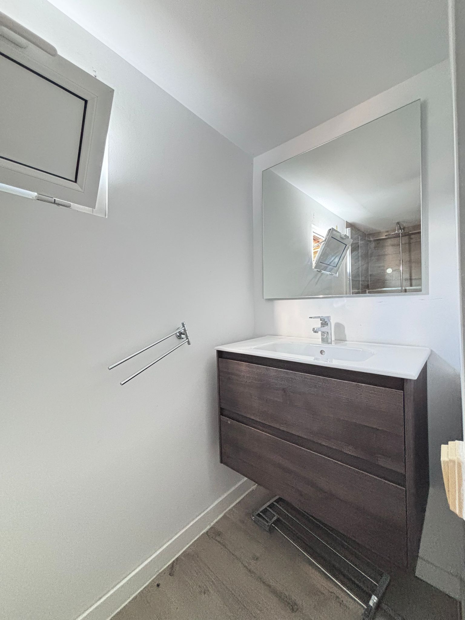 Baño pequeño y moderno con lavabo con mueble, espejo y toallero de pared.
