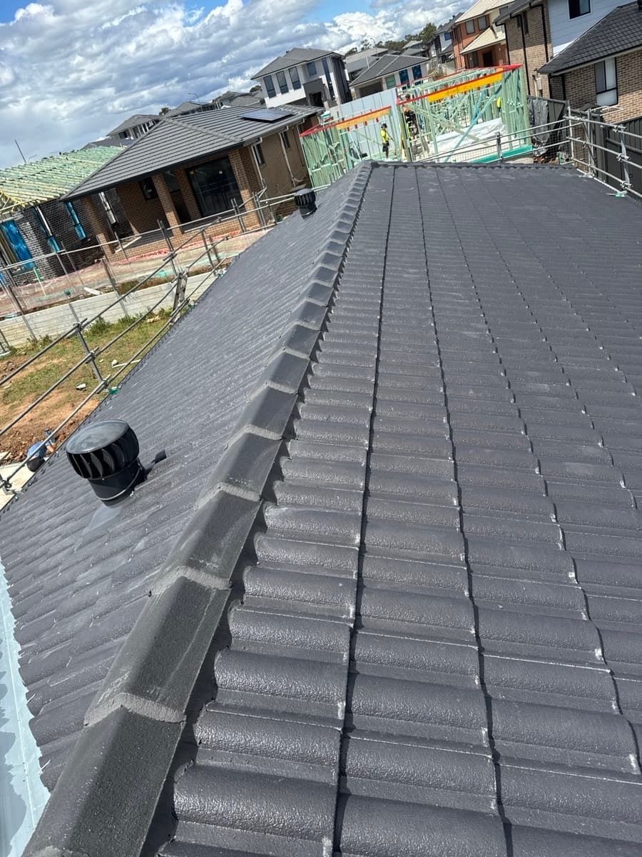 Roofing under construction with black shingles and workers’ scaffolding on a cloudy day
