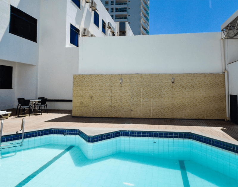 Uma pequena piscina em um pátio com um prédio branco e bege.