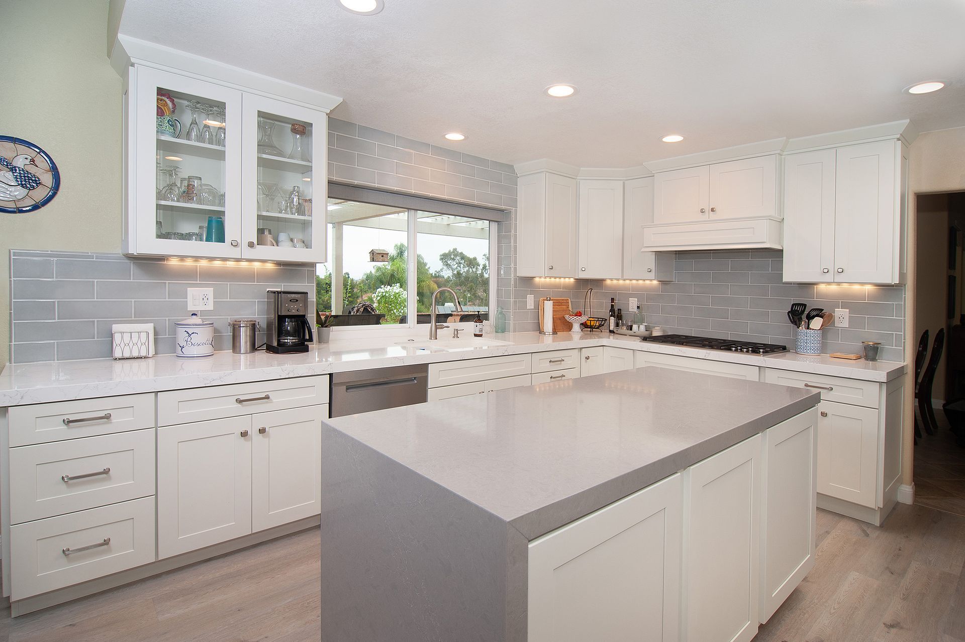 Bright, modern kitchen with white cabinets, grey backsplash, and a large central island with a grey countertop.
