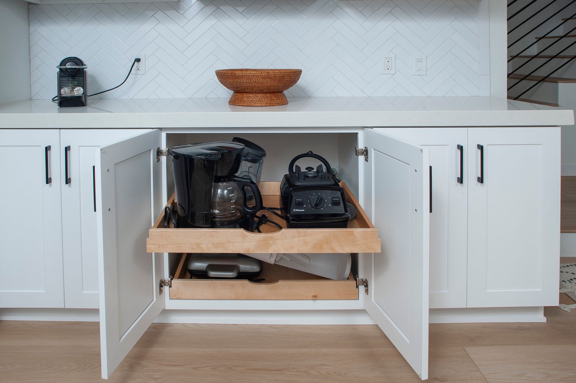 White kitchen cabinet with pull-out shelf holding coffee maker, blender, and other appliances.