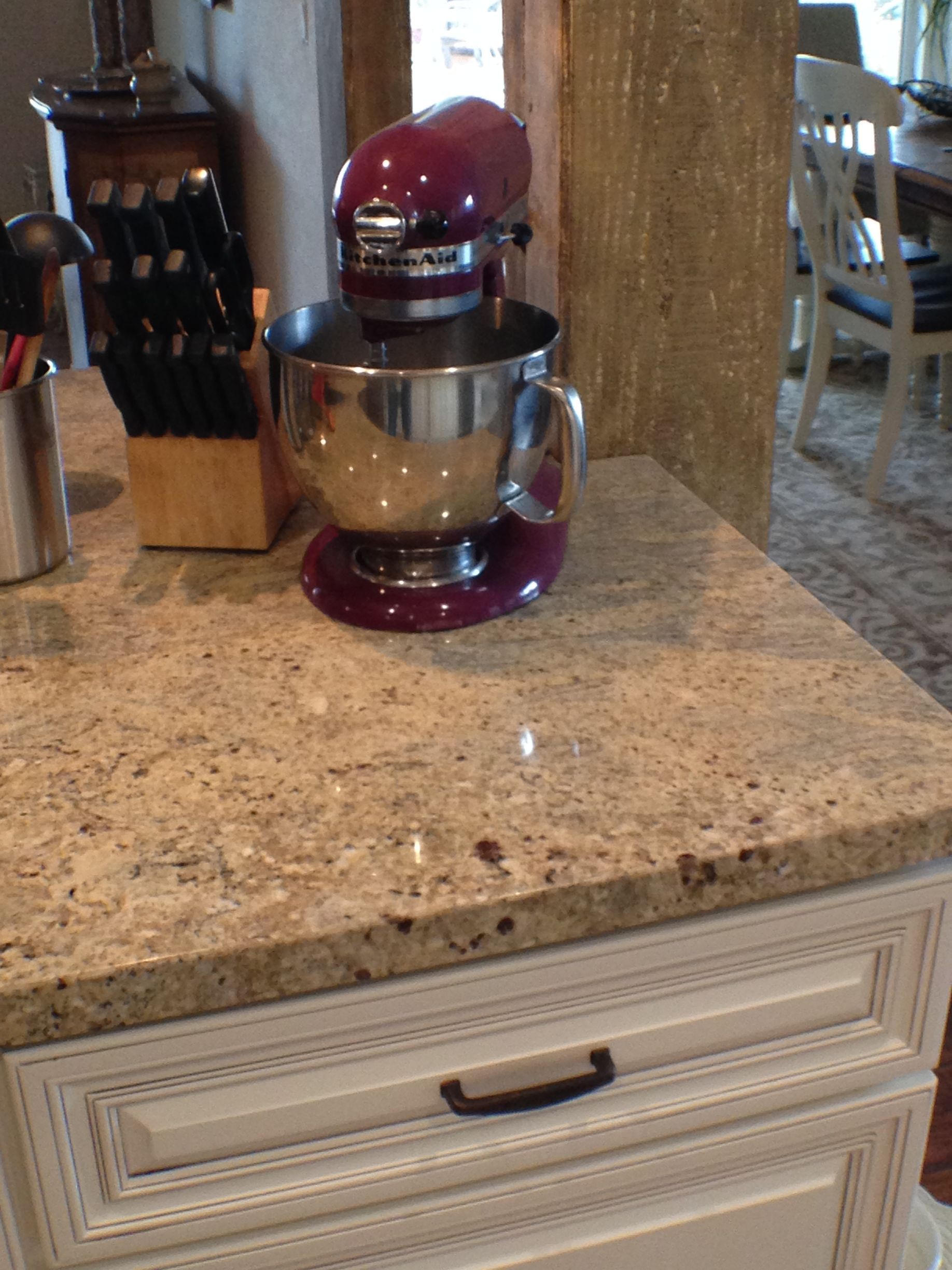 Kitchen counter with a purple KitchenAid mixer, knife block, and white cabinets.