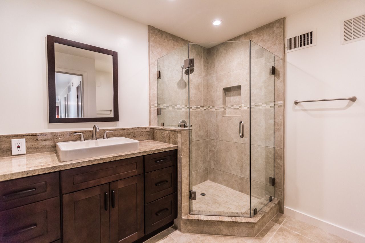 Modern bathroom with a shower, vanity, and brown cabinets.