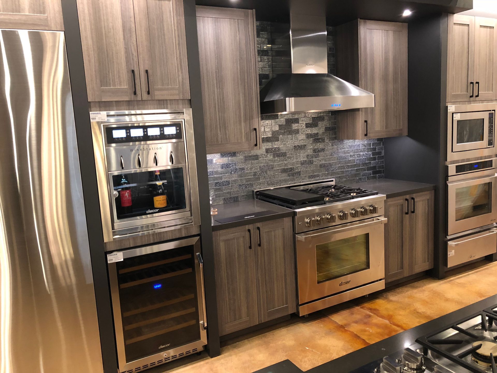 Modern kitchen with stainless steel appliances, wood cabinets, and a brick-style backsplash.