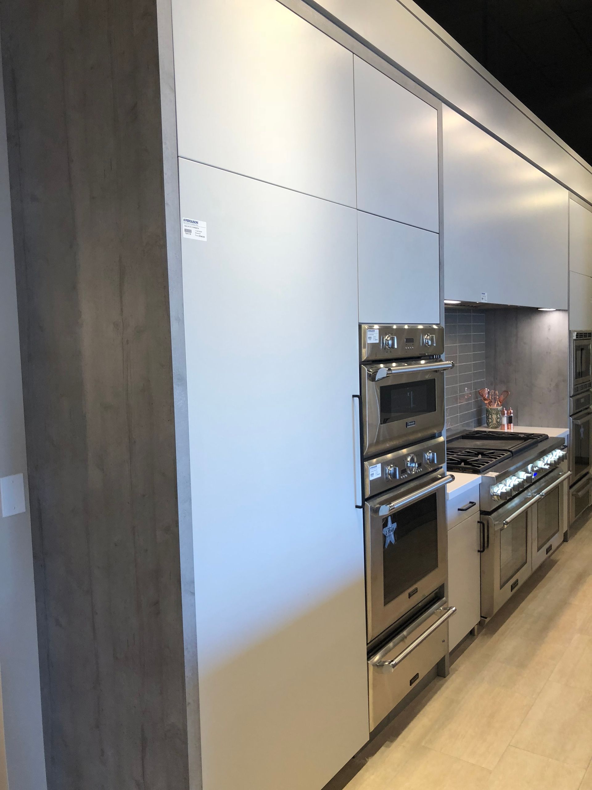 Modern kitchen with light gray cabinets, stainless steel appliances.