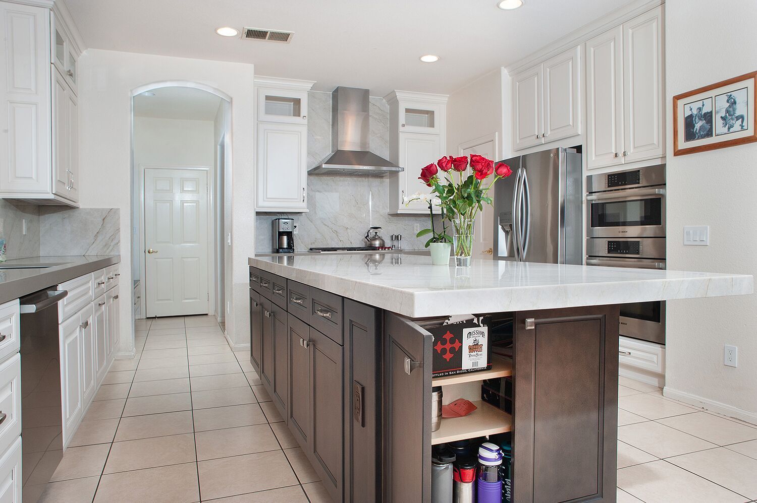 Modern kitchen with white and gray cabinets, marble countertops, and a central island.