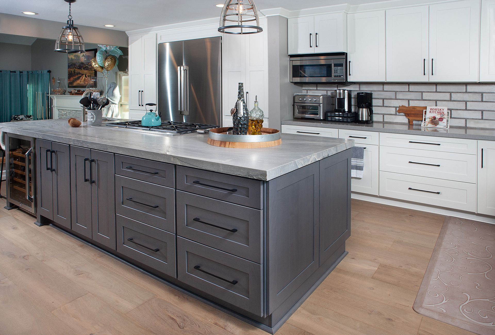 Modern kitchen with gray island and white cabinets; stainless steel appliances.
