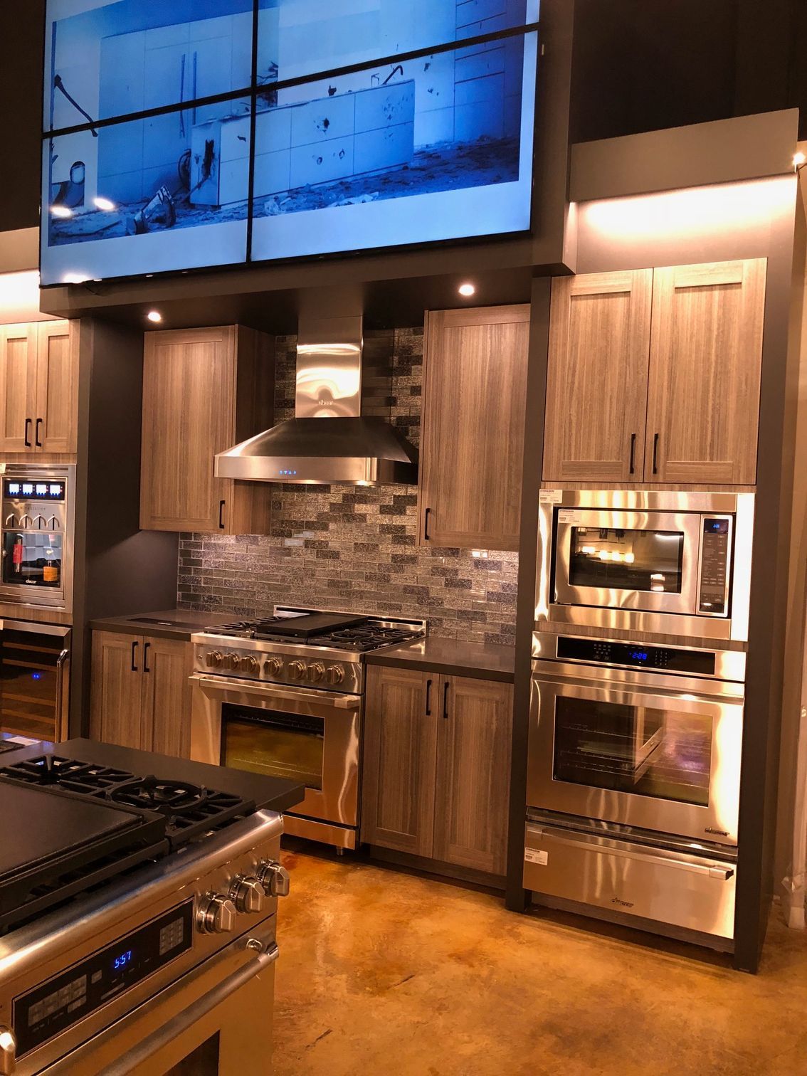 Modern kitchen with stainless steel appliances, wood cabinets, and a stone backsplash.