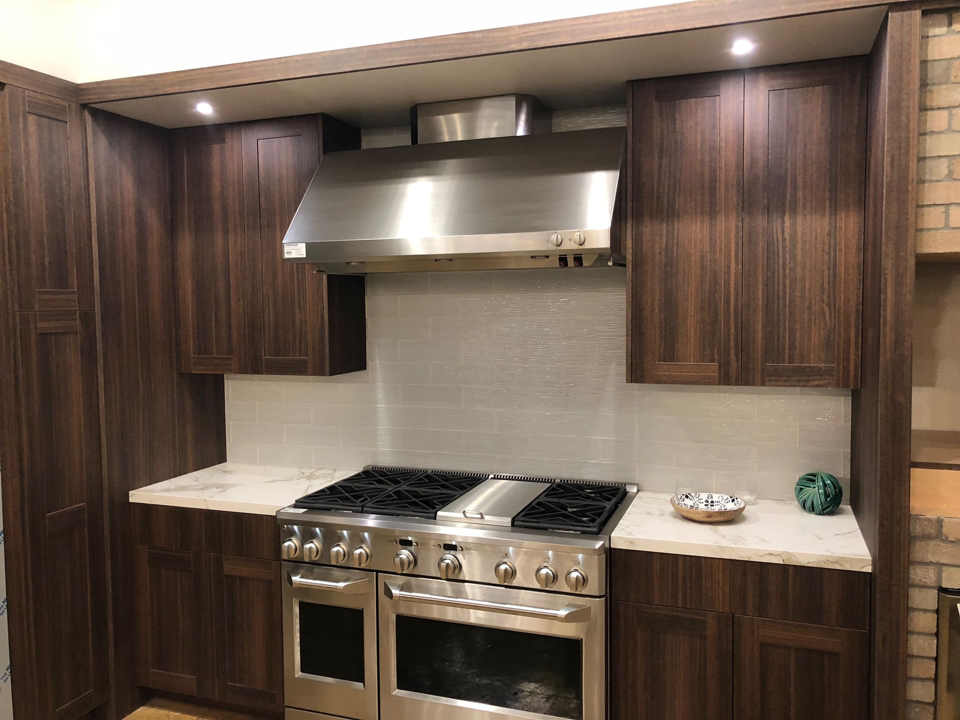 Dark wood kitchen cabinets with a stainless steel stove and range hood; white countertops.