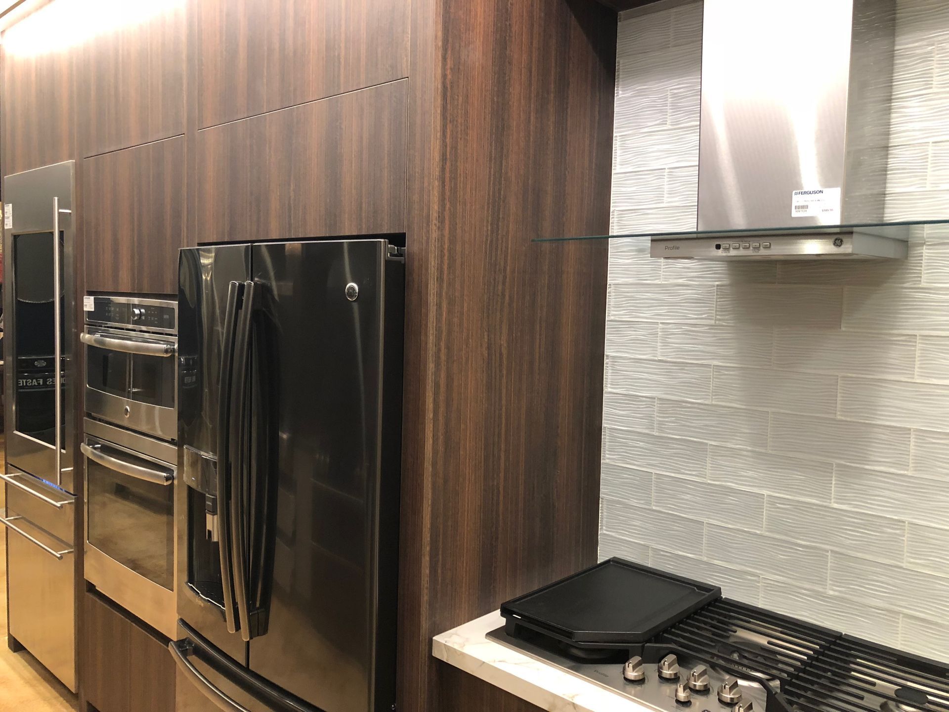 Stainless steel appliances, dark wood cabinets, tile backsplash, range.