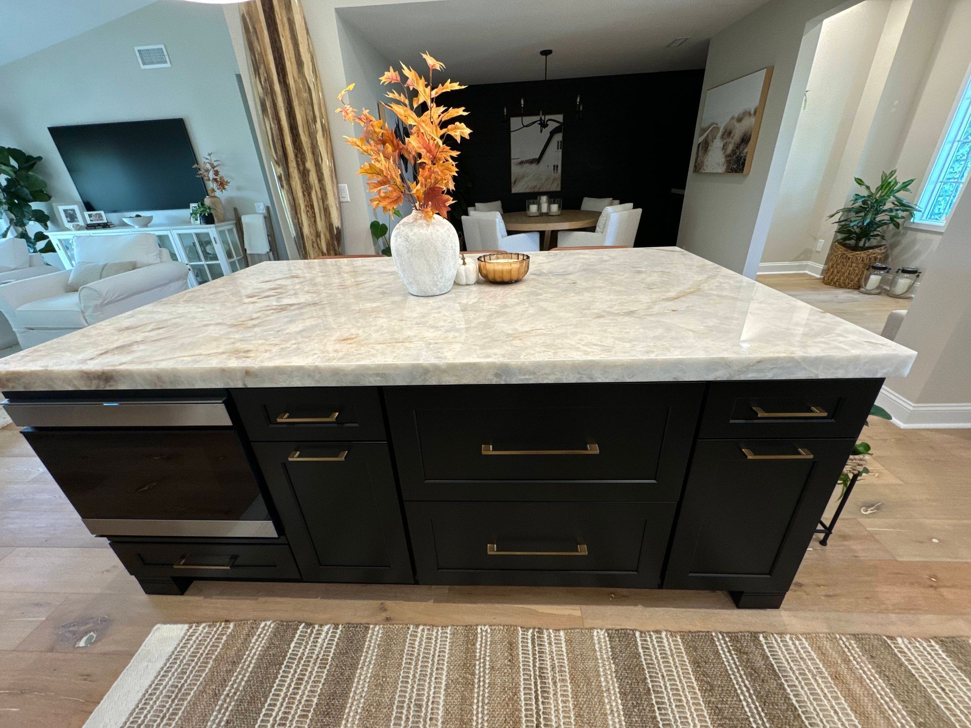 Kitchen island with black cabinets and light countertop; vase of orange flowers.