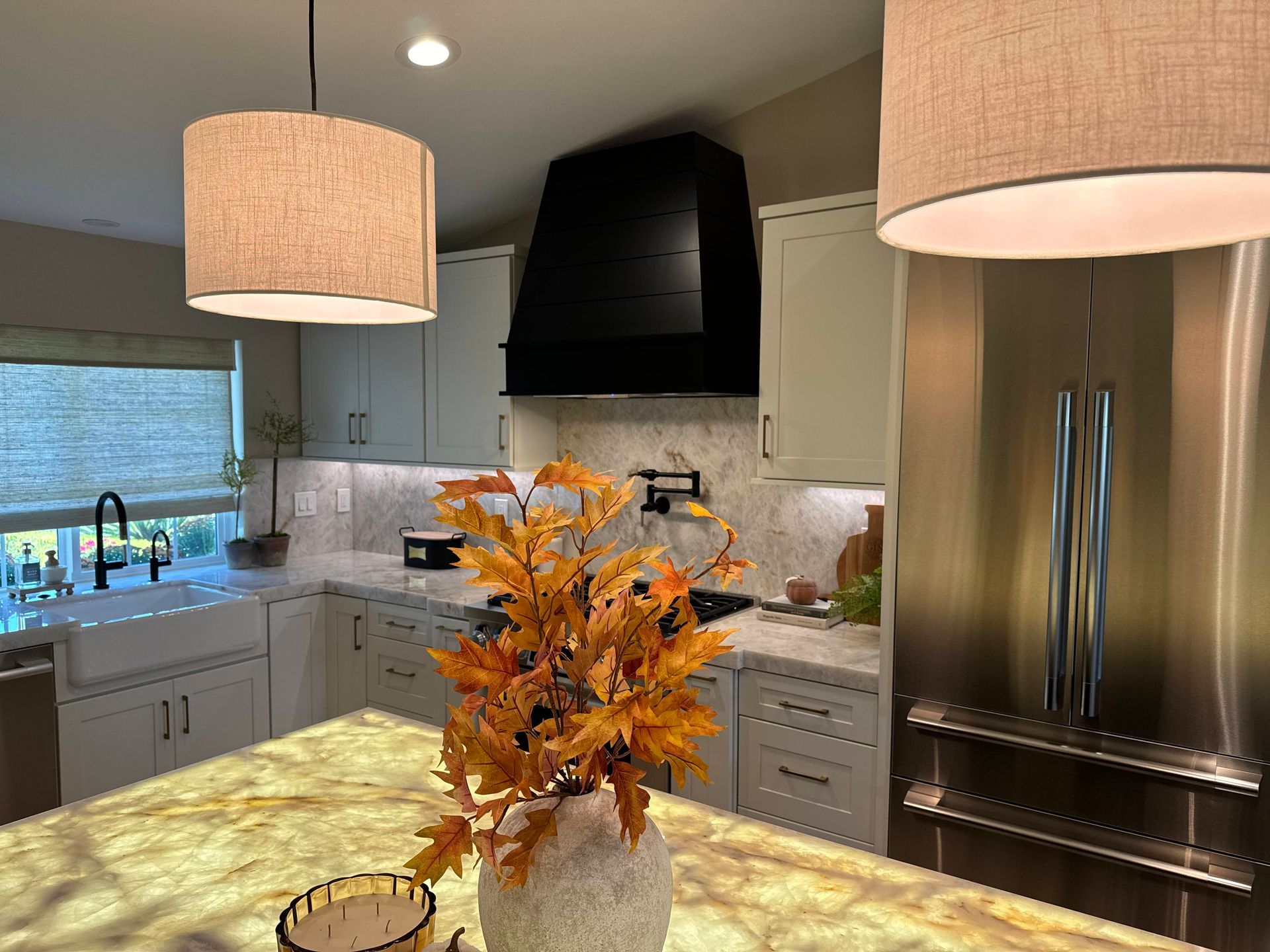 Kitchen with white cabinets, black range hood, and gold pendant lights.