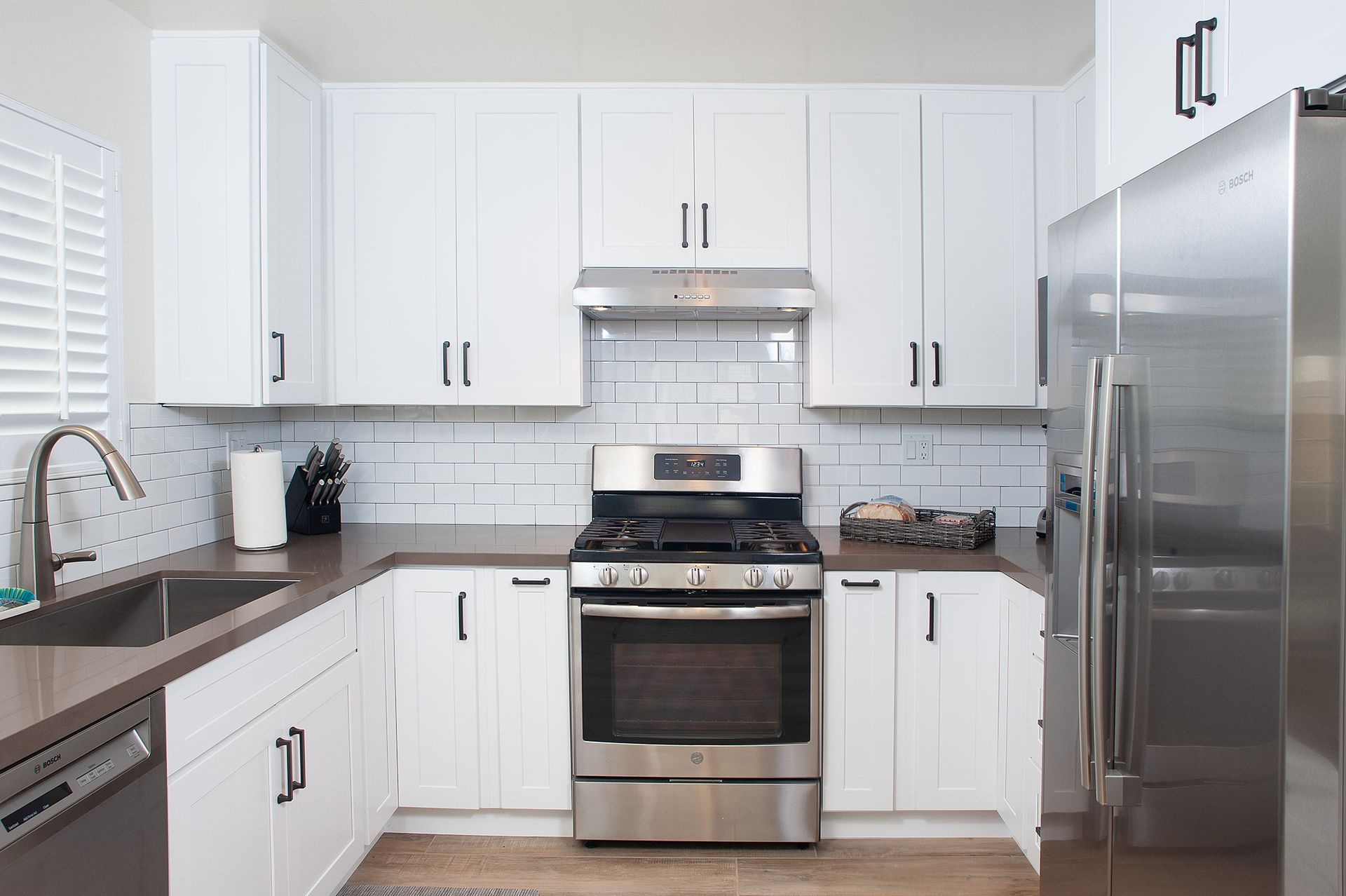White kitchen with stainless steel appliances and dark countertops.