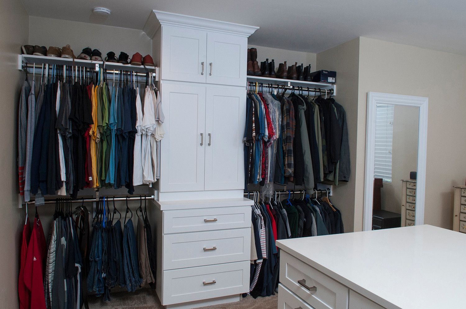 A walk in closet with lots of clothes and a mirror