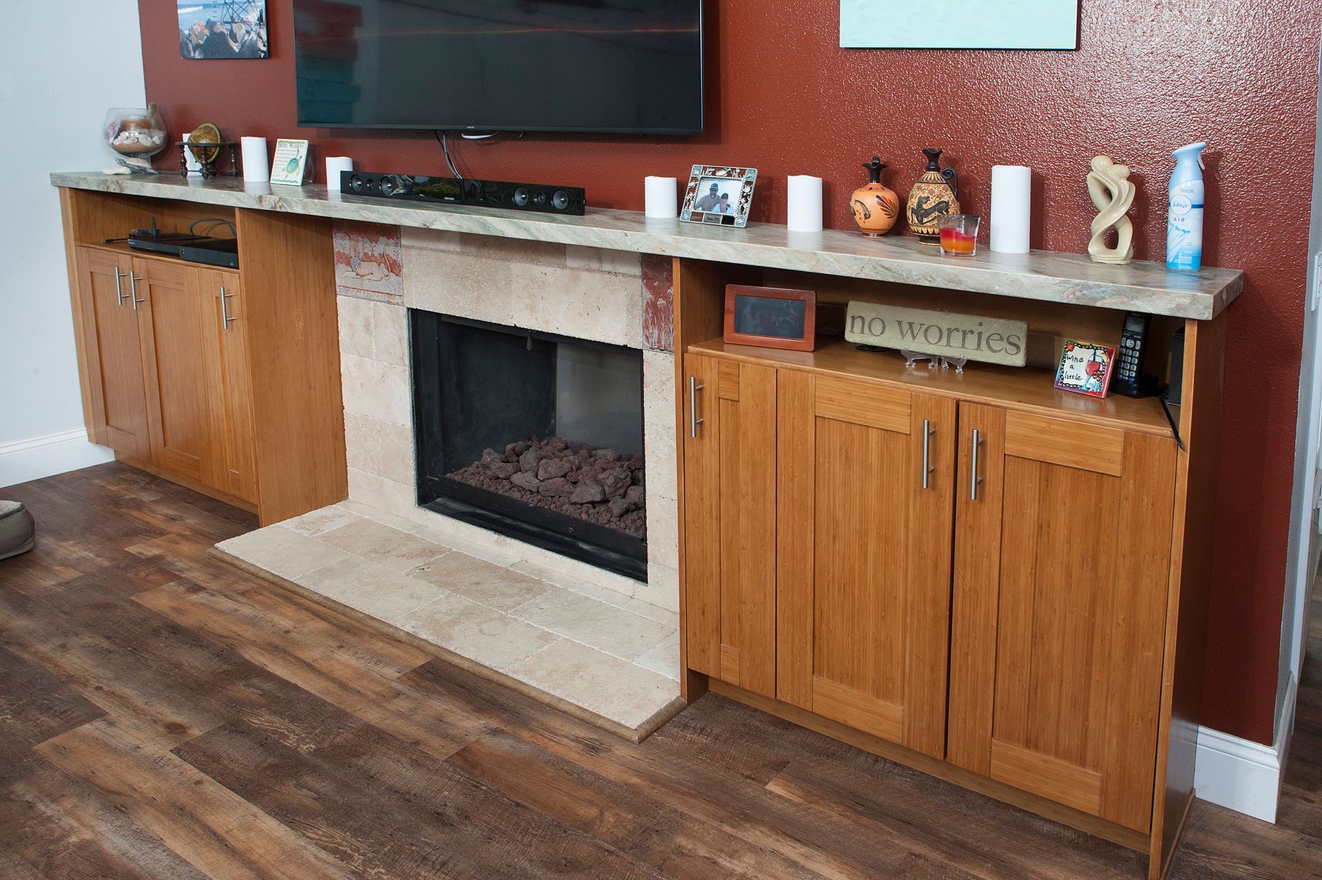 Fireplace with cabinets, TV, and decorations against a red wall and wood floor.