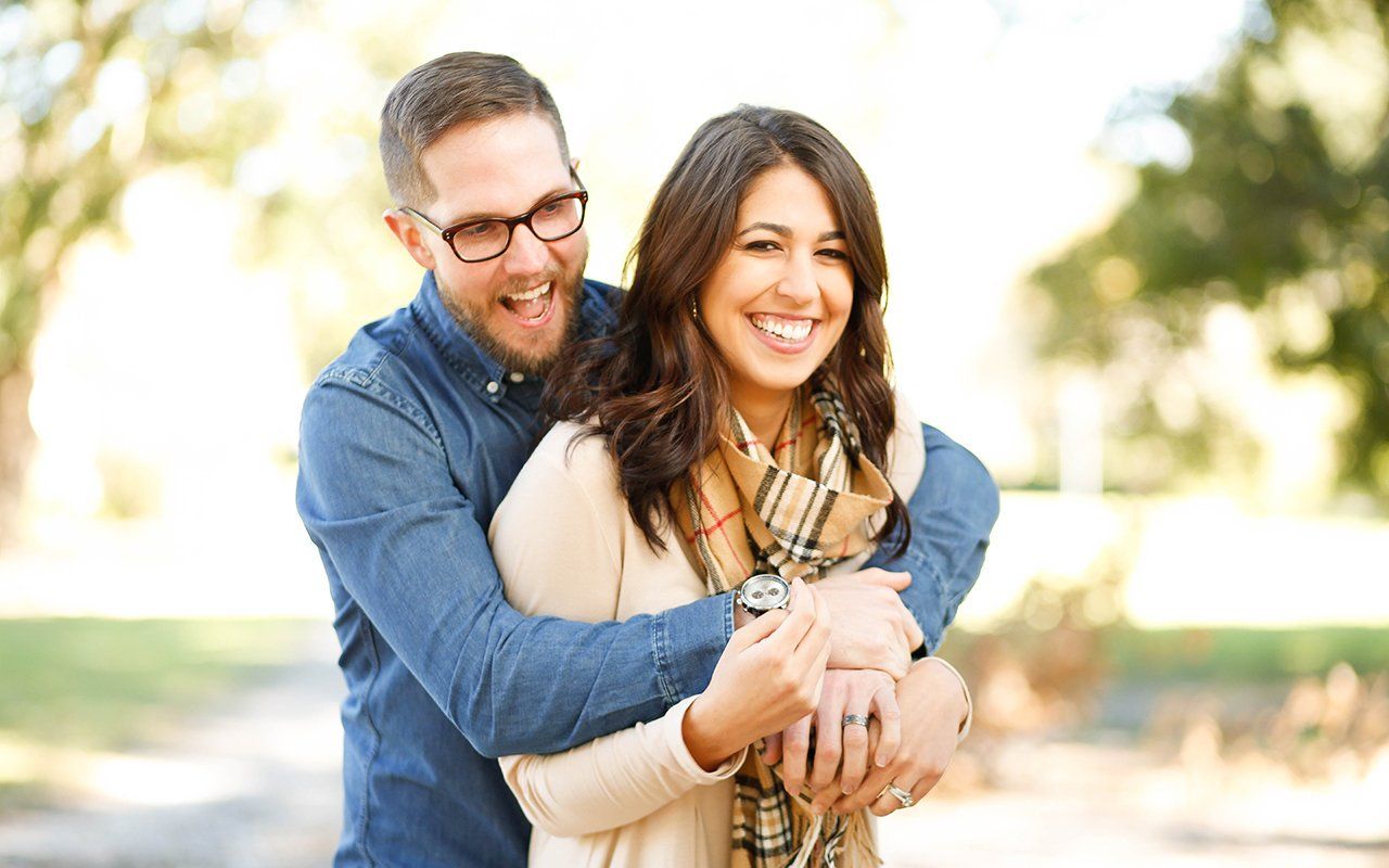 A man is hugging a woman in a park.