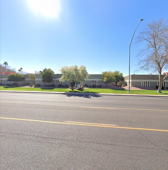 A street with a building in the background and trees on the side