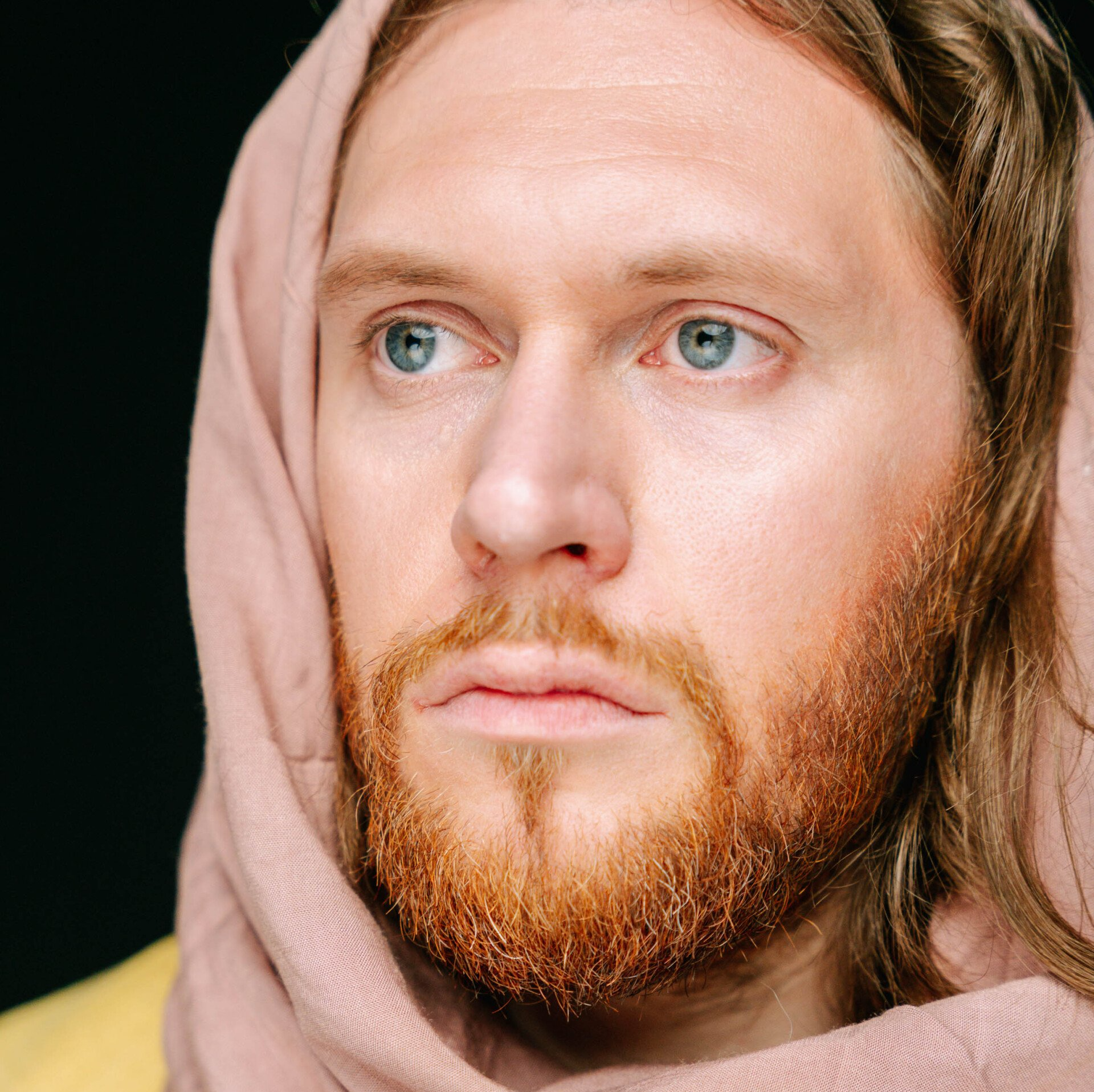 A man with a beard is wearing a pink scarf around his neck