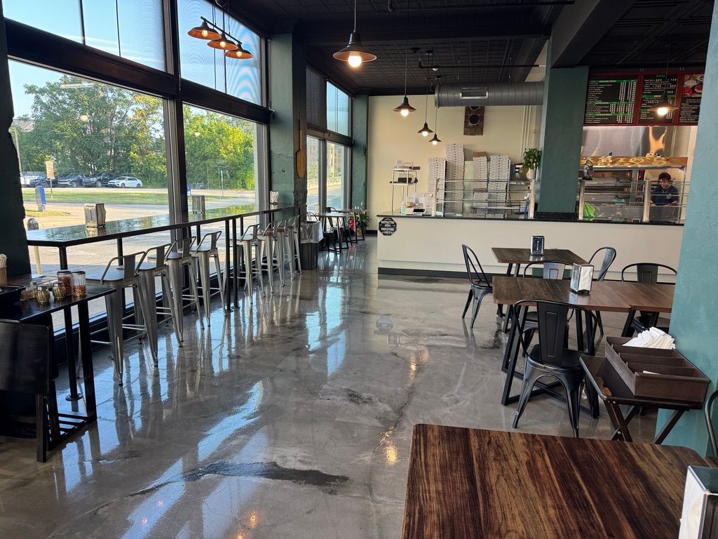 Empty modern cafe interior with large windows, polished floor, and black tables and chairs