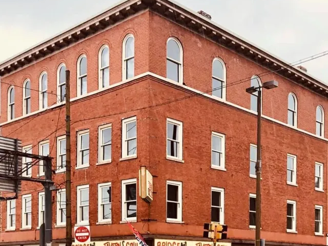 Red brick corner building with white-trimmed windows at a city intersection