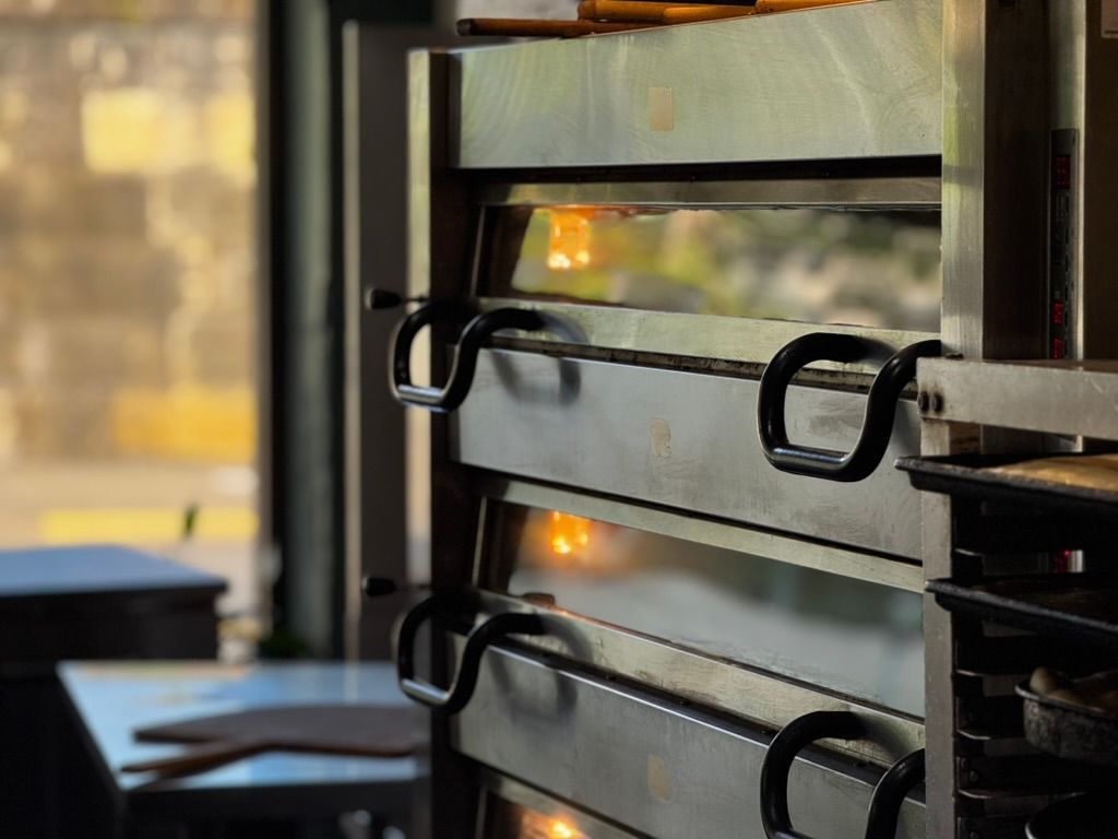 Stacked metal oven racks with reflections in a warm-lit kitchen or bakery window
