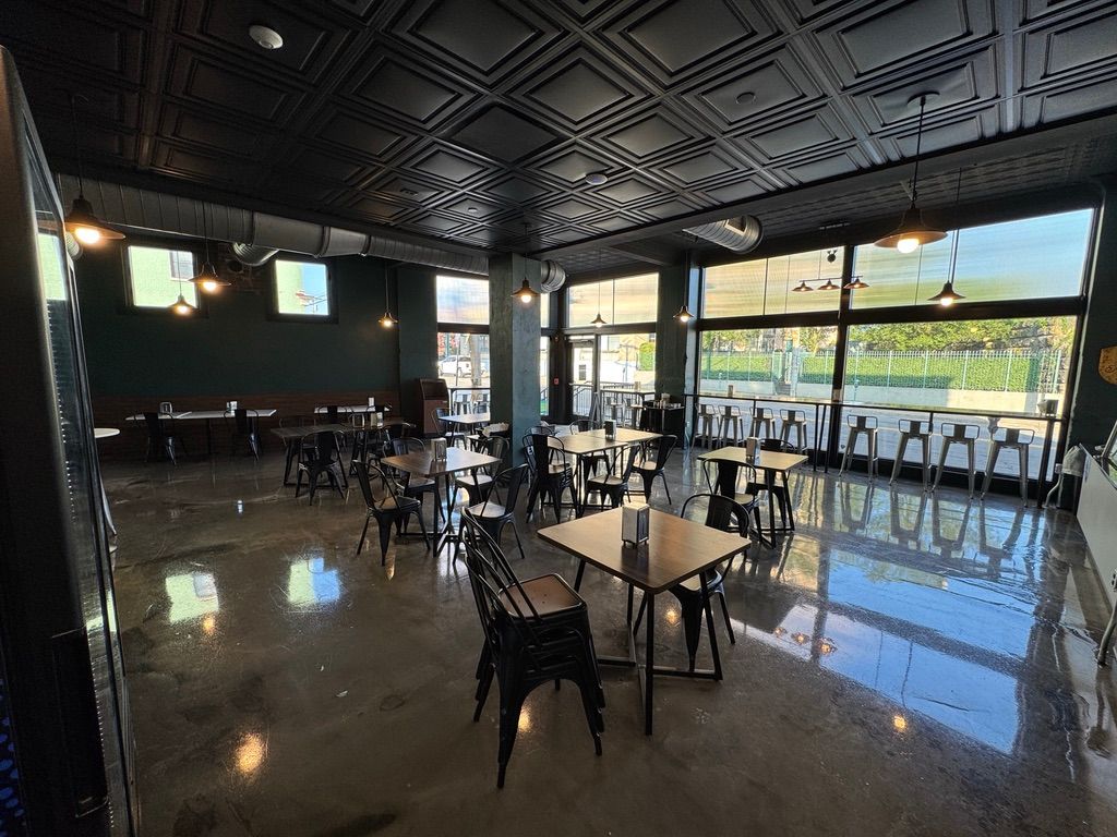 Modern café interior with black chairs, wooden tables, and bright sunlight from large windows