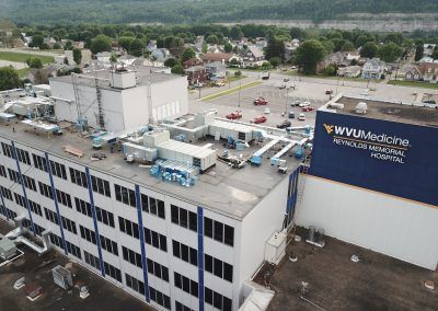 Aerial view of WVU Medicine hospital building and rooftop equipment in a suburban area