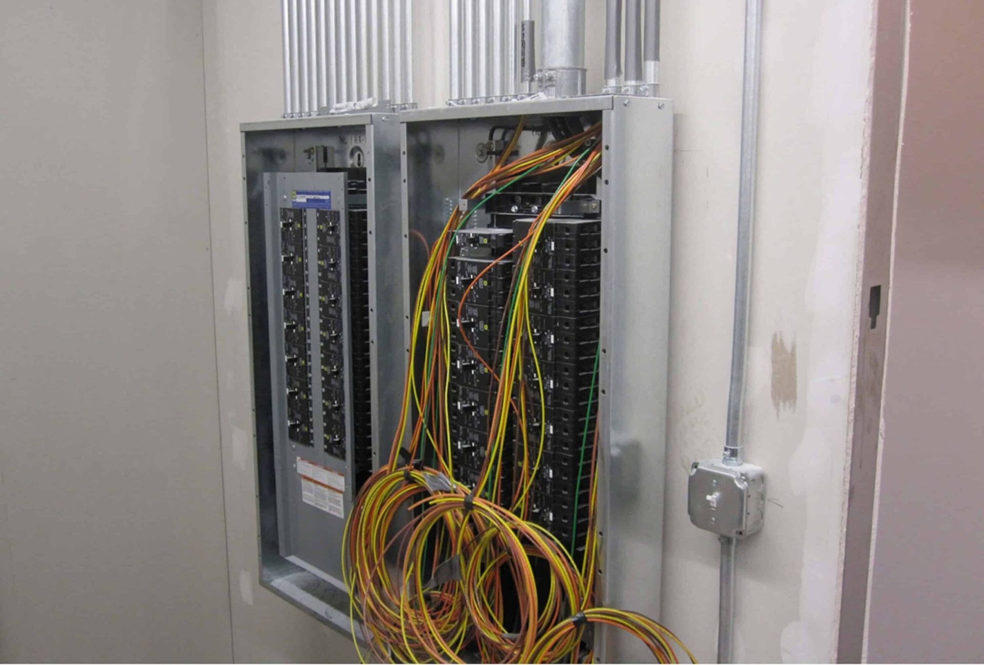 Open electrical panel with exposed wiring and network cables in a utility closet