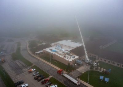 Foggy aerial view of a modern building with parking lot and winding roads nearby
