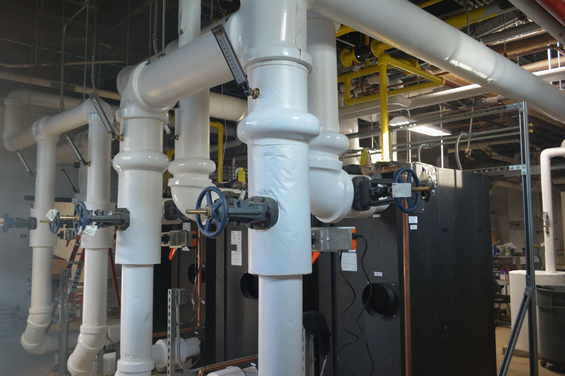 Industrial equipment with large white pipes and black machinery in a factory interior