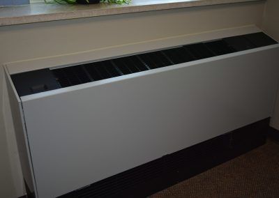 White wall-mounted radiator cover beneath a window in a room