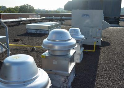 Rooftop HVAC vents and ductwork on a flat commercial roof under daylight.