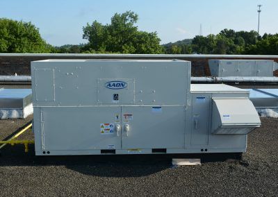 Large white rooftop HVAC unit on a flat roof under a clear sky